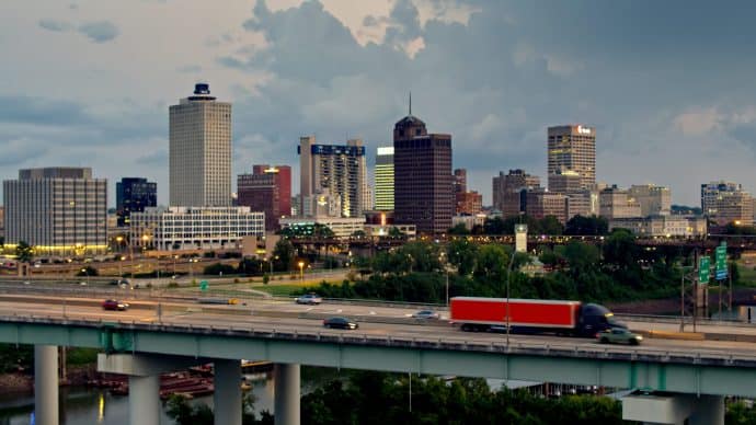 Aerial shot of Memphis, Tennessee, looking across the ramp of the Hernando de Soto Bridge towards the downtown skyline with dramatic storm clouds behind.